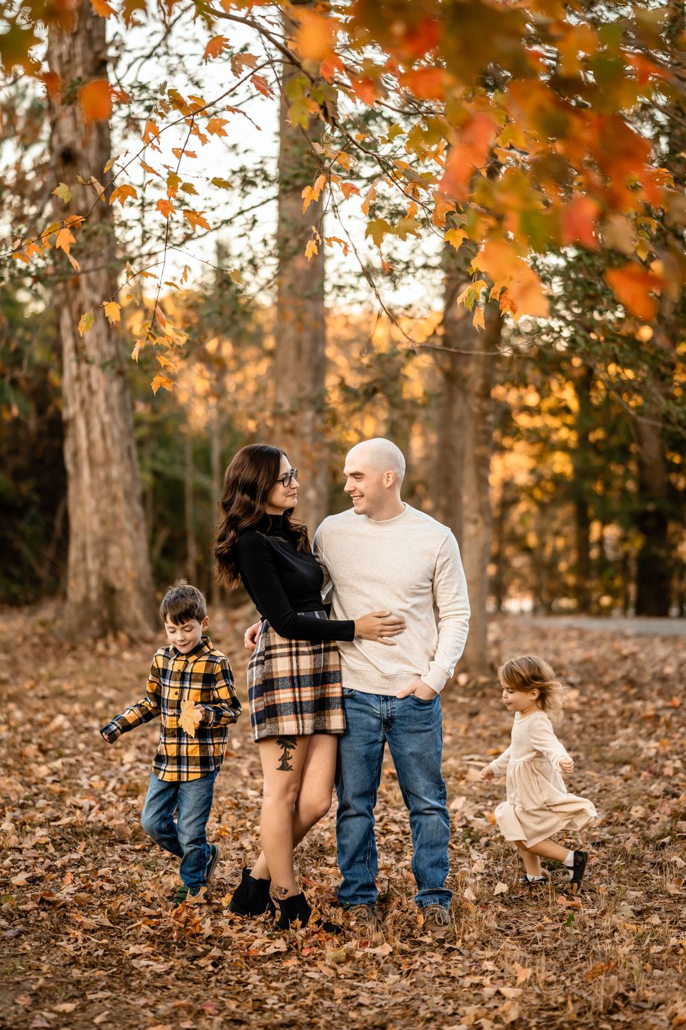 Family enjoying autumn day together in park with falling leaves and warm sunlight.
