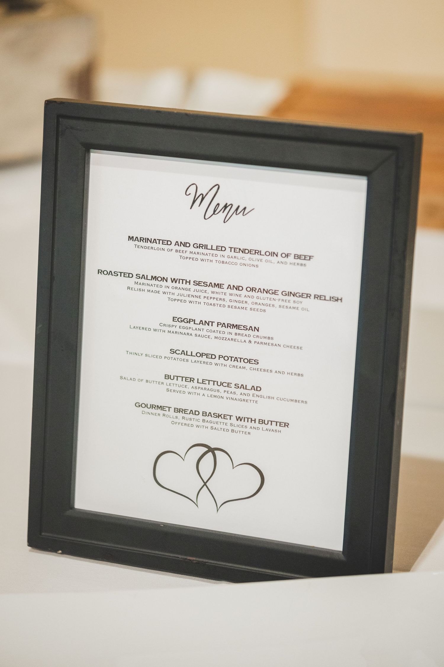 Wedding menu in black frame featuring elegant script and decorative hearts design.