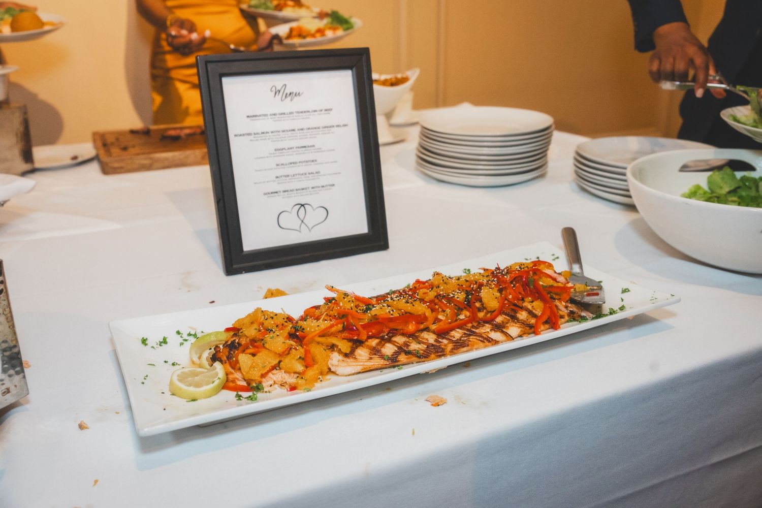 Elegantly plated seafood dish served on white platter with menu display.