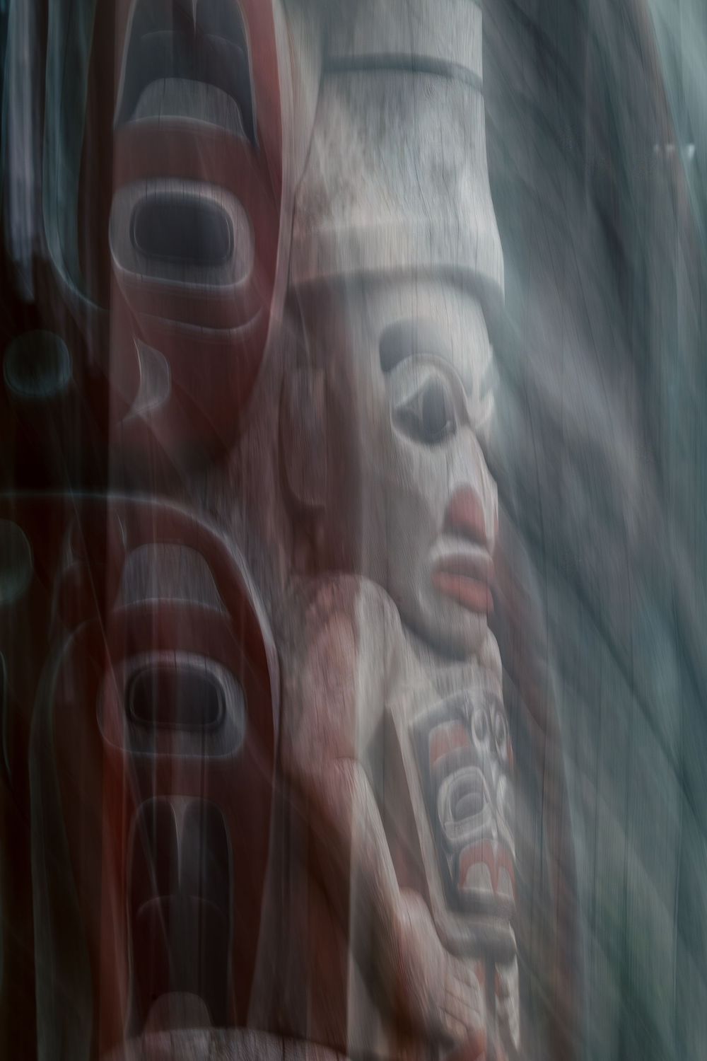 Blurred motion photograph of a colorful Pacific Northwest Native American totem pole with red and black carved faces.