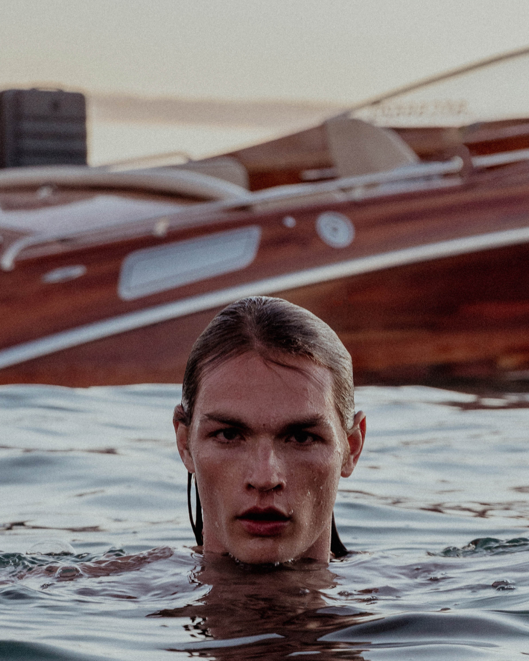 Close-up shot of swimmer emerging from dark water at dusk.