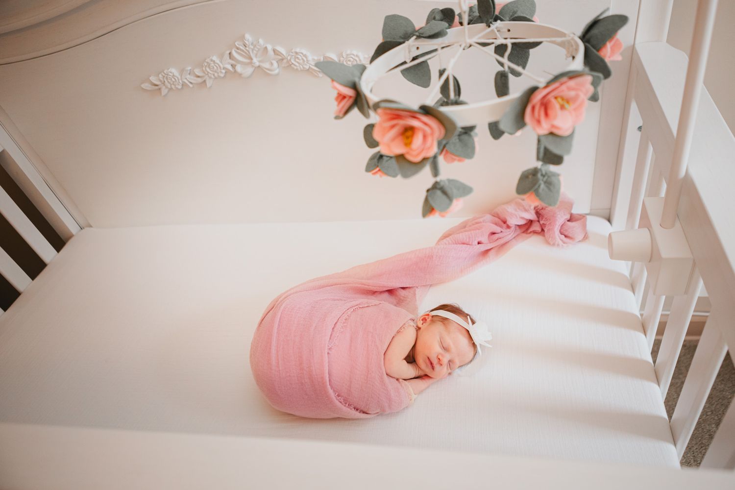 gorgeous newborn photo of a baby resting in her crib with shadowing and flowers