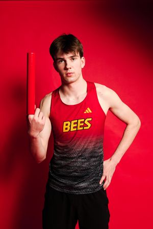 Athletic person in red and black gradient tank top with yellow 'BEES' text poses against vibrant red background.