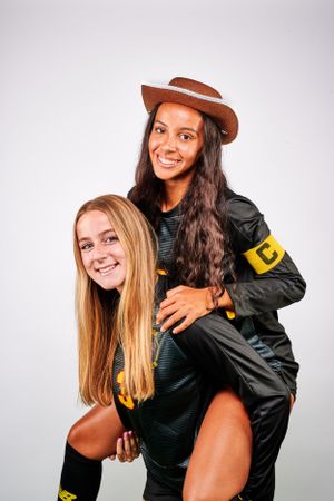 Two athletes in black and yellow uniforms posing playfully against white background. Brecksville Ohio soccer.