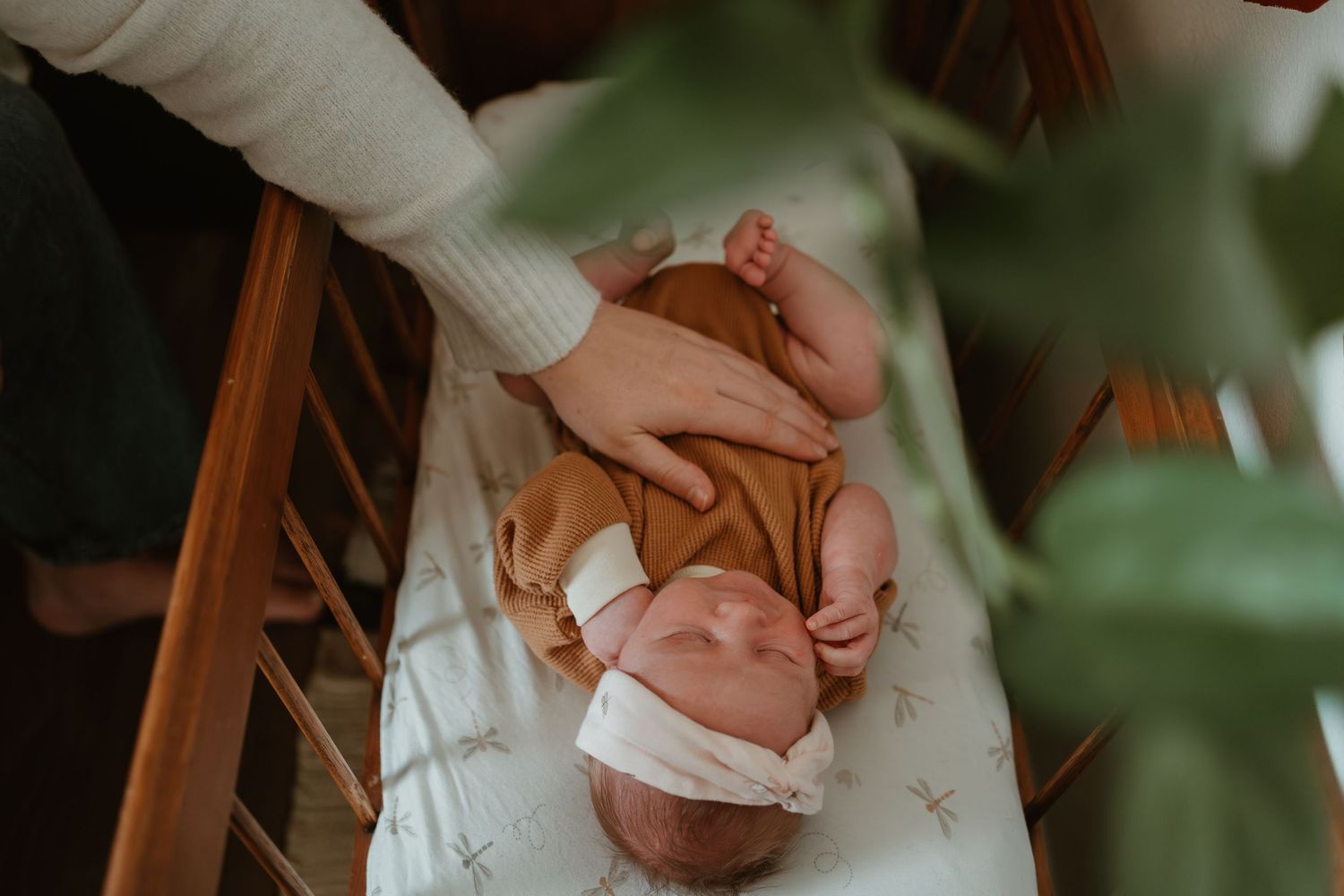 Sleeping newborn baby wearing a floral dress in a moody portrait.