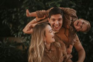 Joyful family moment captured outdoors with natural foliage backdrop.