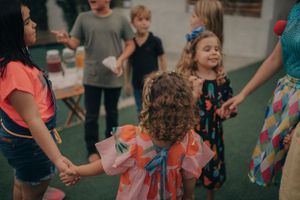 Children holding hands in a circle while playing party games on indoor turf.