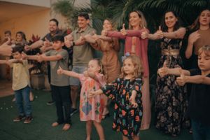 Families standing in a line doing a synchronized dance or movement activity at a group gathering.