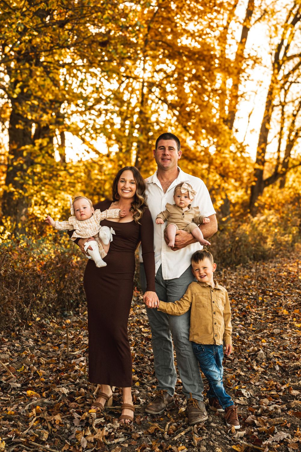 A family of 5 posing for a portrait amongst the fall foliage.