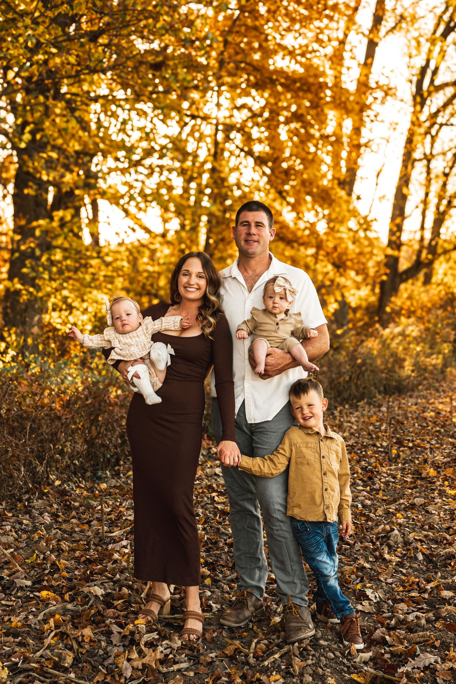 A family of 5 posing for a portrait amongst the fall foliage.