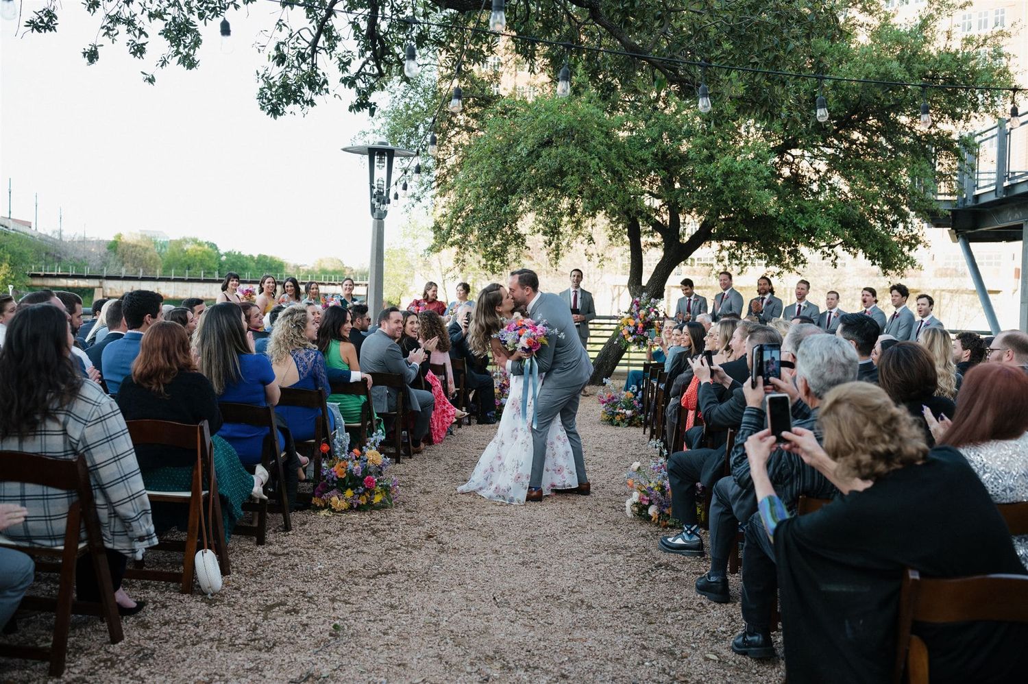 Wedding guests watch a couple dancing under oak trees at an outdoor ceremony in Charleston.