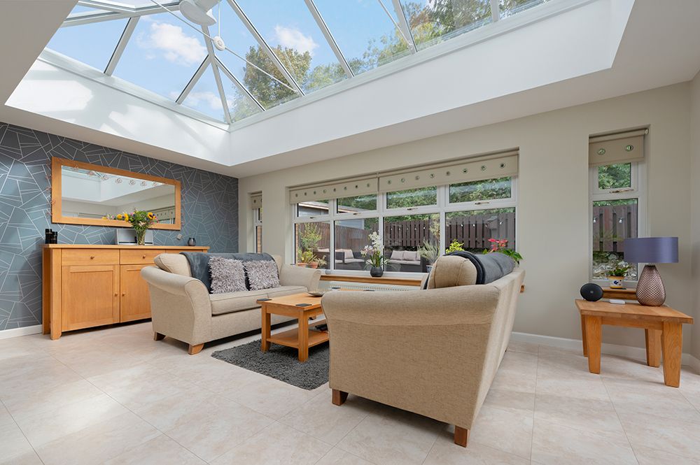Modern family room with skylights features beige furniture and wooden accents in an open floor plan design.