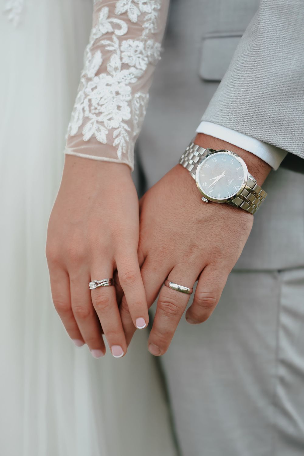 Close up of newlyweds' hands showing wedding rings and watches.