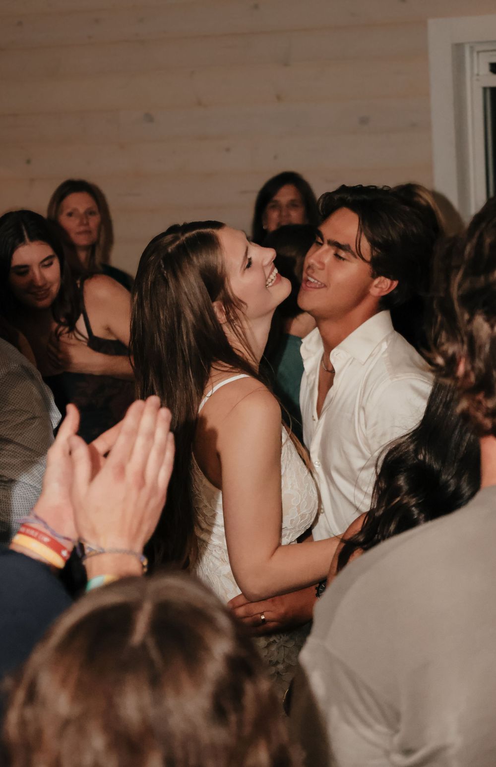 Wedding reception dancing scene with guests celebrating in a rustic indoor venue.