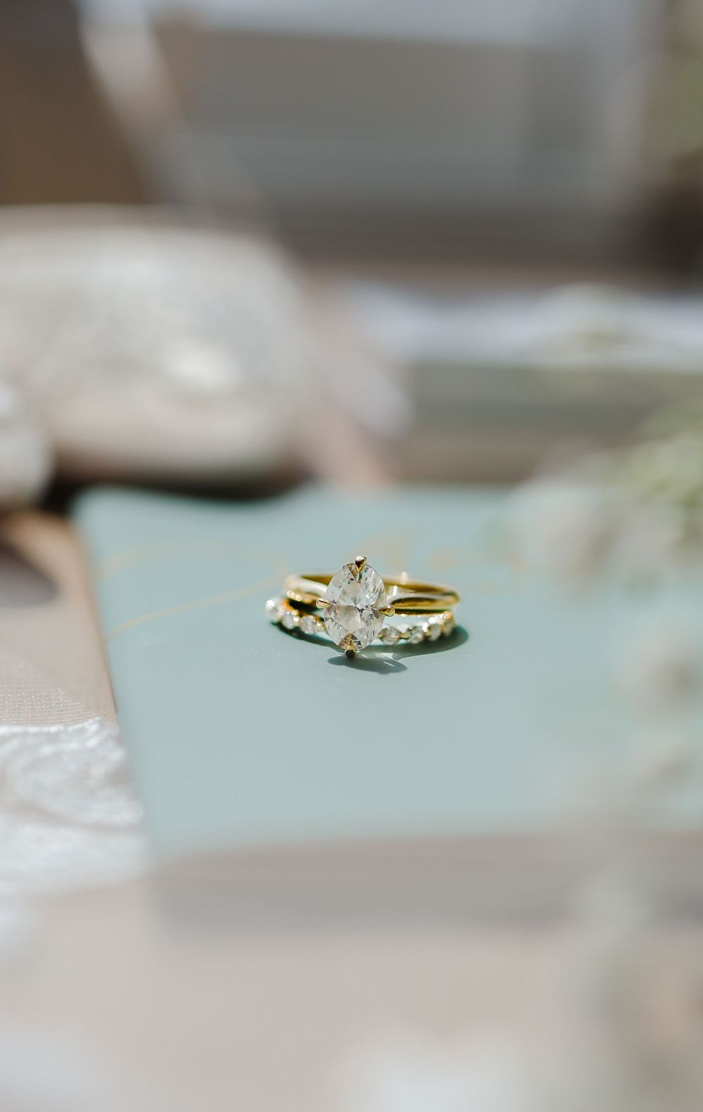 Close-up of an elegant diamond engagement ring on a mint-colored surface.