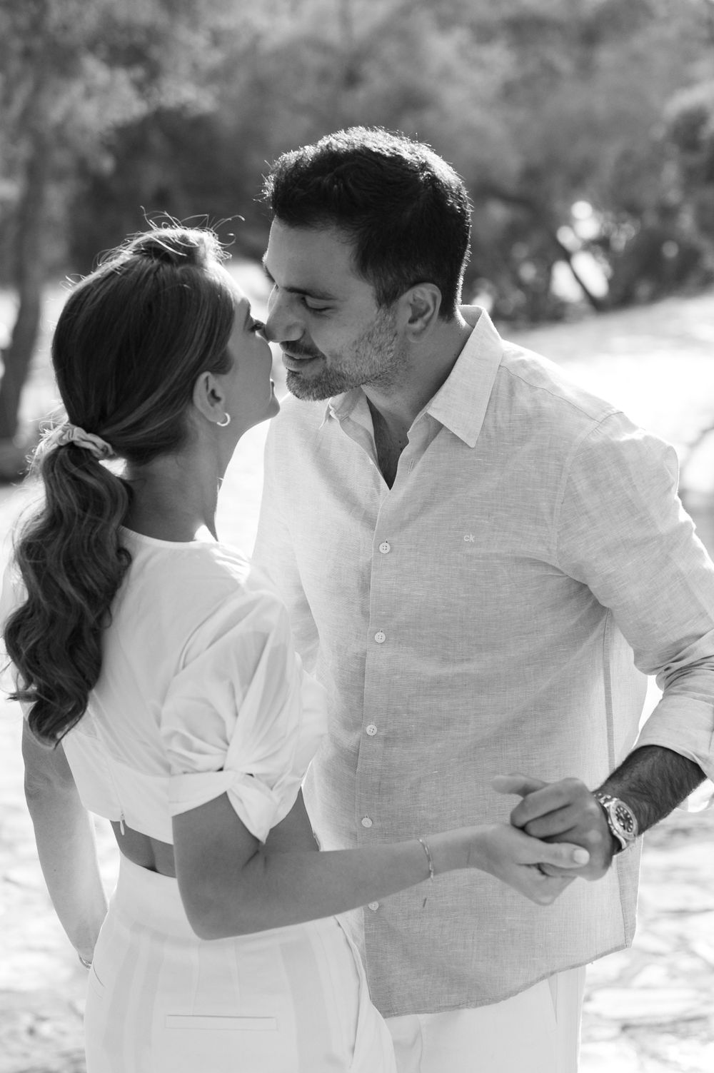 A romantic black and white portrait of a couple dancing outdoors.