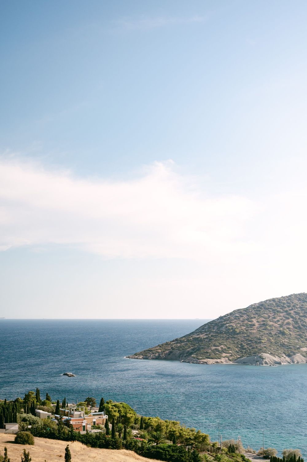 Scenic Mediterranean coastline view with blue waters and rocky hillside under clear skies.
