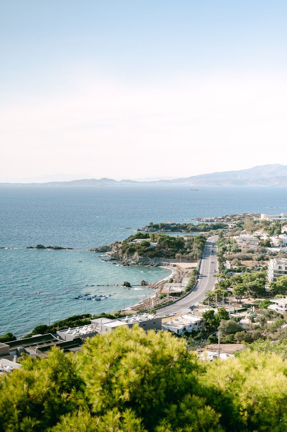 Coastal road winding along Mediterranean shoreline with turquoise waters and seaside houses.