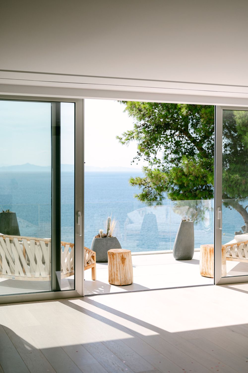 Modern sliding glass doors open to ocean view terrace with wooden accent pieces.