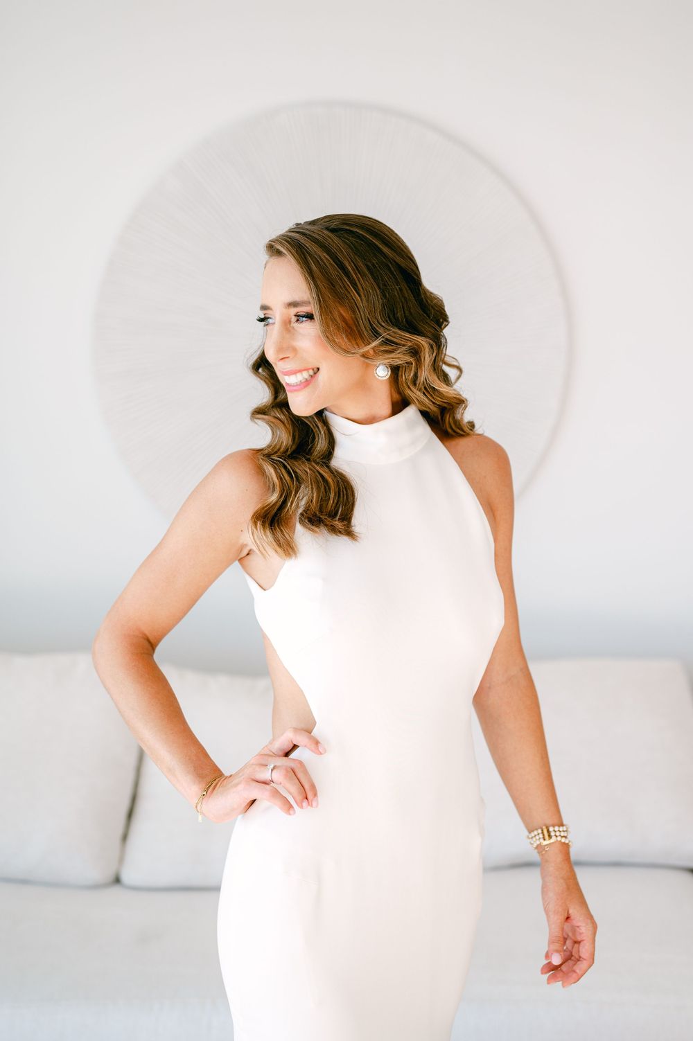 Elegant bridal portrait in a fitted white halter dress against a minimalist backdrop.