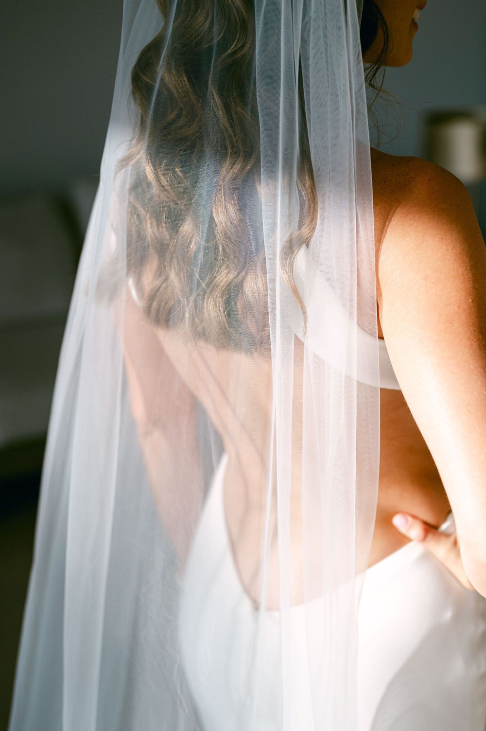 Soft detail shot of flowing bridal veil and wavy hair from behind.