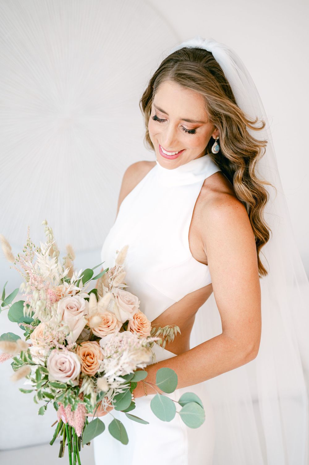 Bridal portrait with a romantic bouquet of peach and pink roses with eucalyptus.
