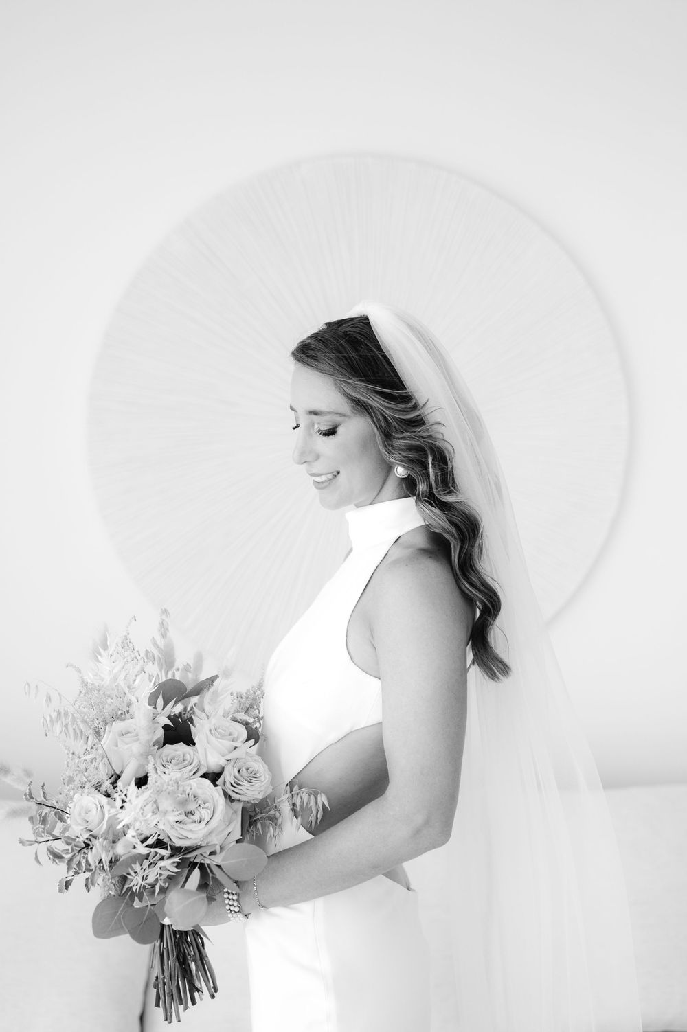 Black and white bridal portrait with bouquet against circular wall art.