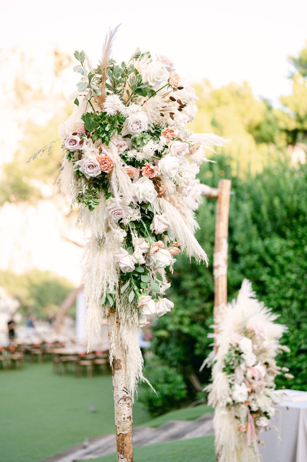 A luxurious wedding ceremony arch decorated with pampas grass, roses, and delicate white flowers.