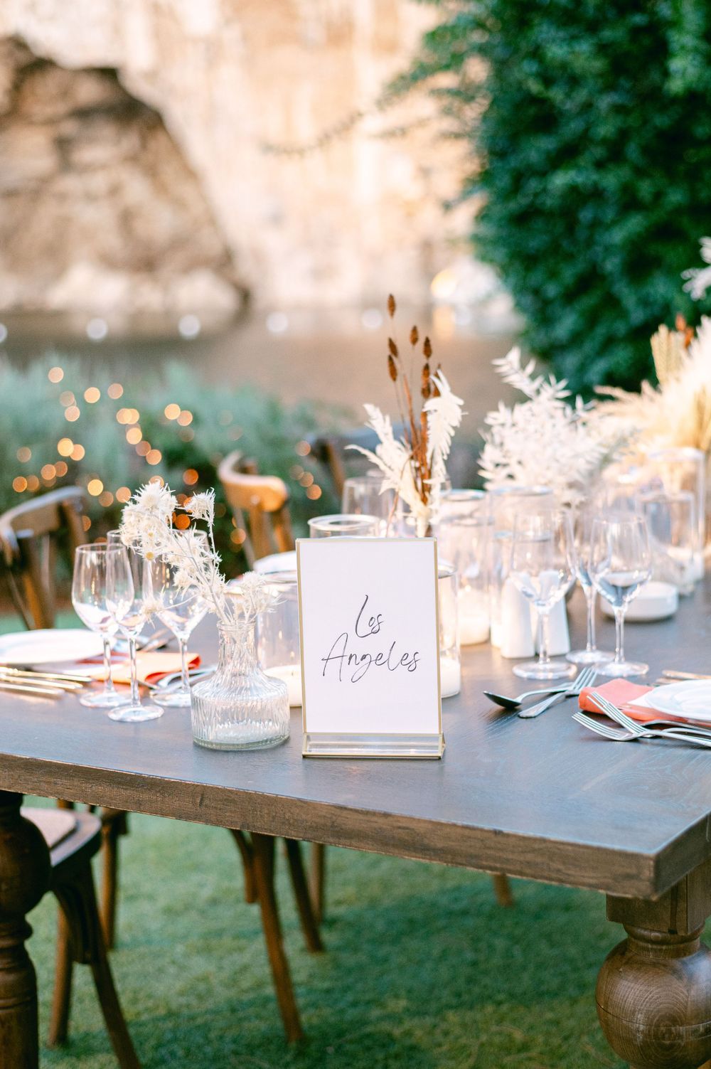 An elegant table setting with wine glasses, place cards, and dried flower arrangements.
