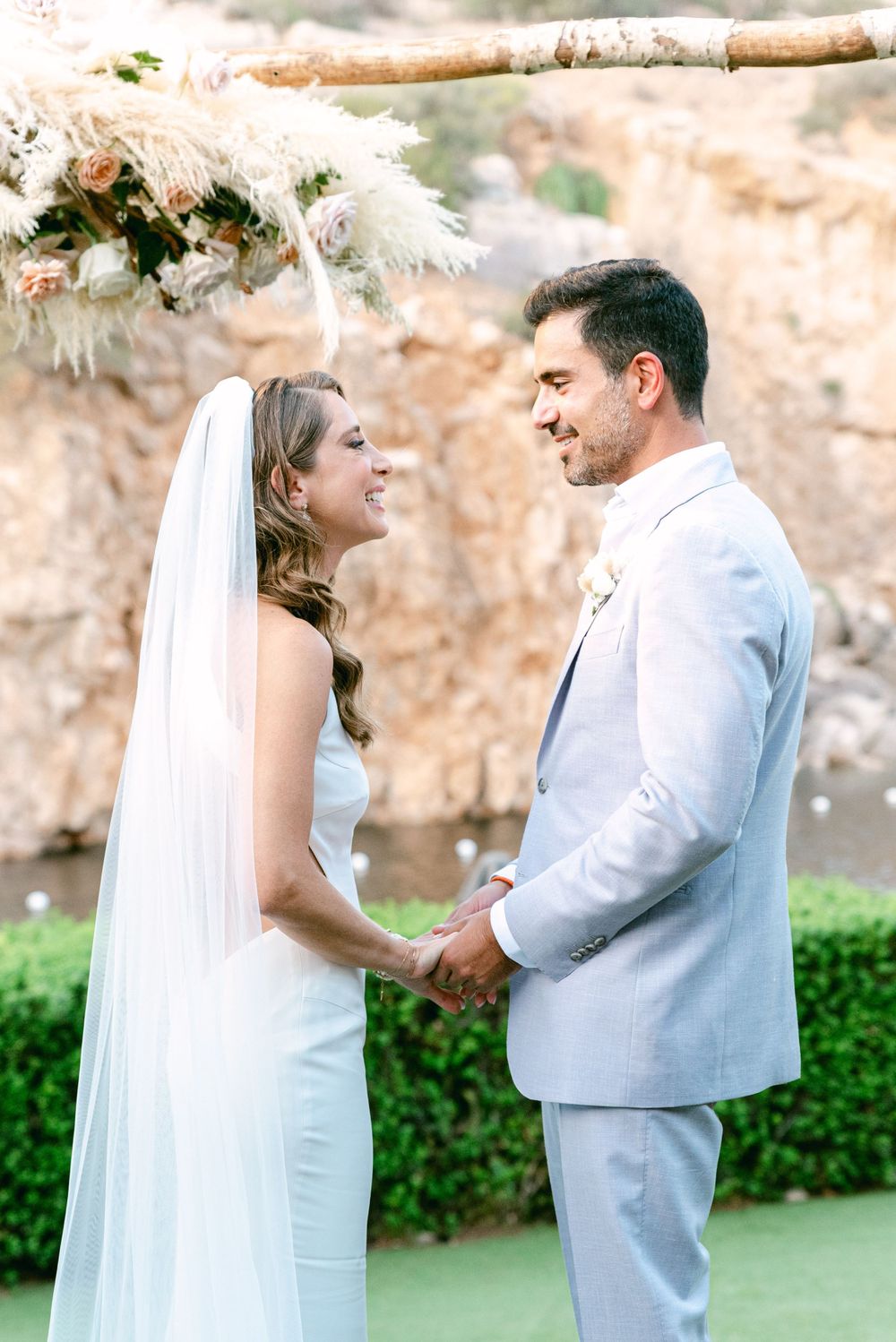 A beautiful outdoor wedding ceremony setup with white floral arrangements and pampas grass decorations.