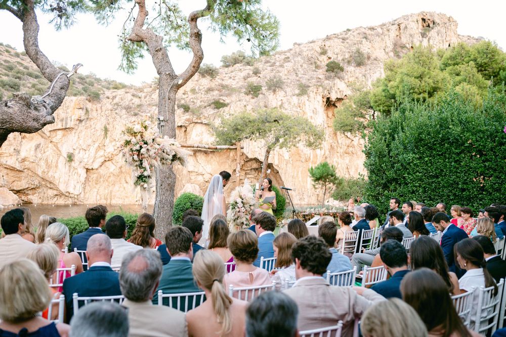 Wedding guests seated in white chairs watching a ceremony against stunning desert rock formations.