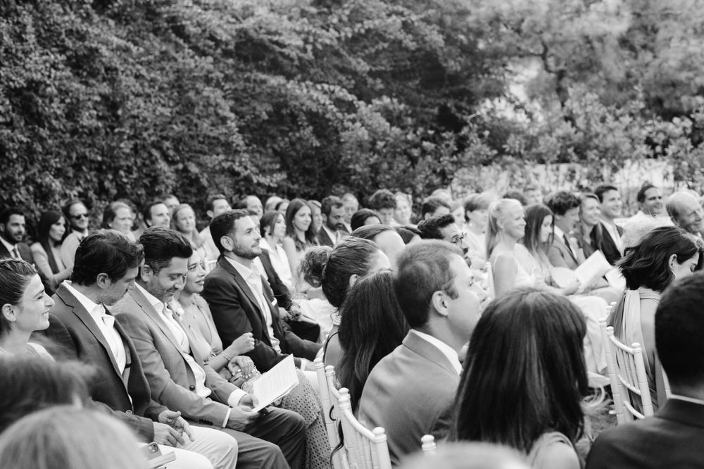 Black and white photo of wedding guests seated outdoors during a garden ceremony.