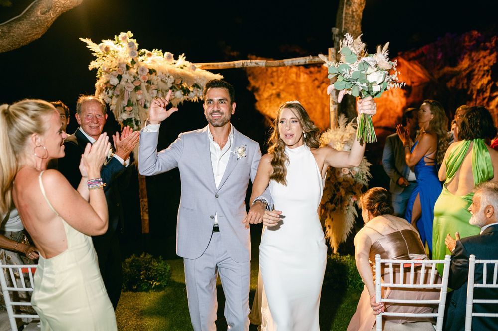Newlyweds celebrate during their reception as guests applaud under evening lighting.