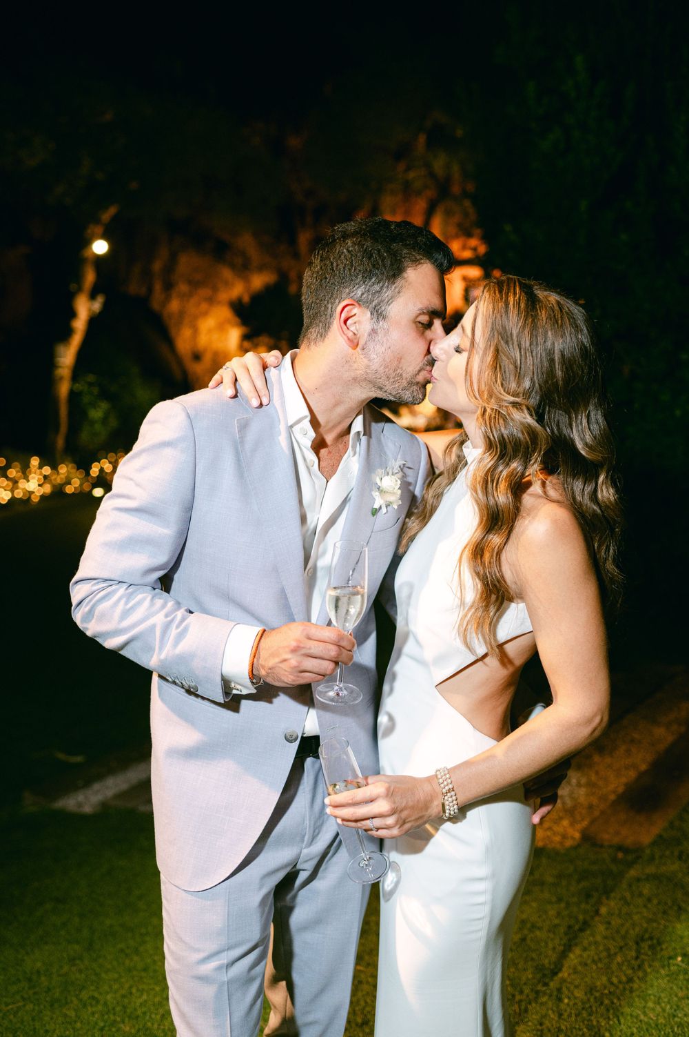 A couple shares a romantic moment while holding champagne glasses at their evening reception.