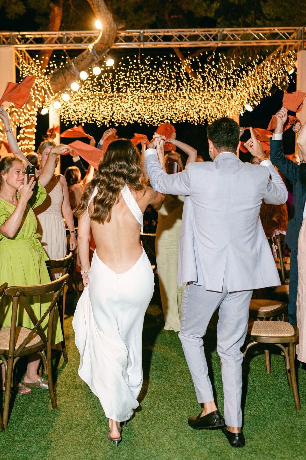 Guests dance beneath a stunning canopy of twinkling string lights at an outdoor wedding reception.