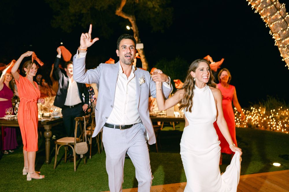 A couple dances joyfully at a nighttime outdoor celebration under glowing lights.