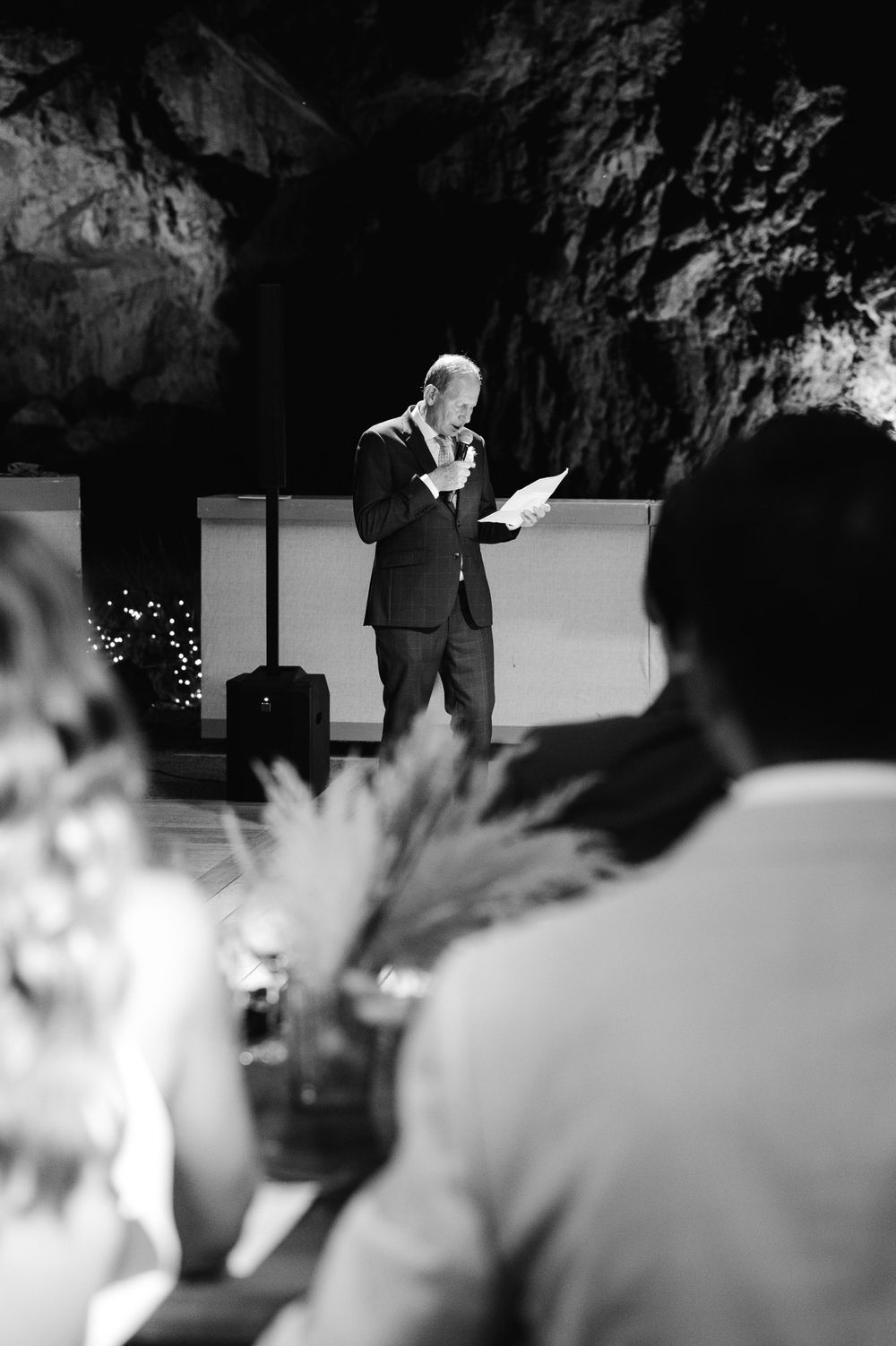 Speaker delivers a speech at an evening event in a dramatic cave-like venue.