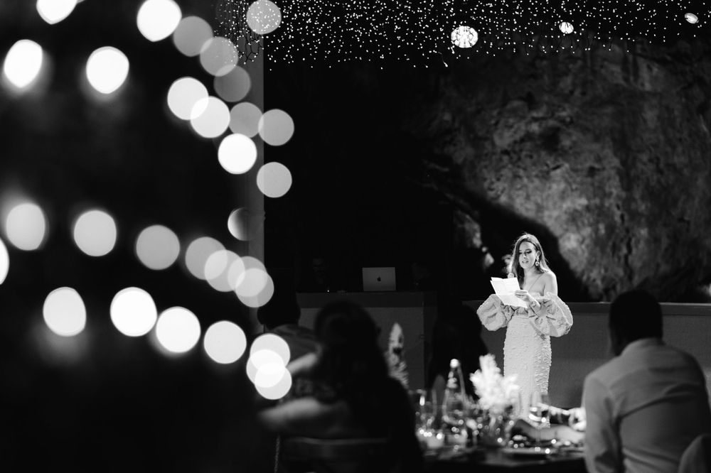 Black and white photo of a speaker at an evening event with dramatic lighting effects.