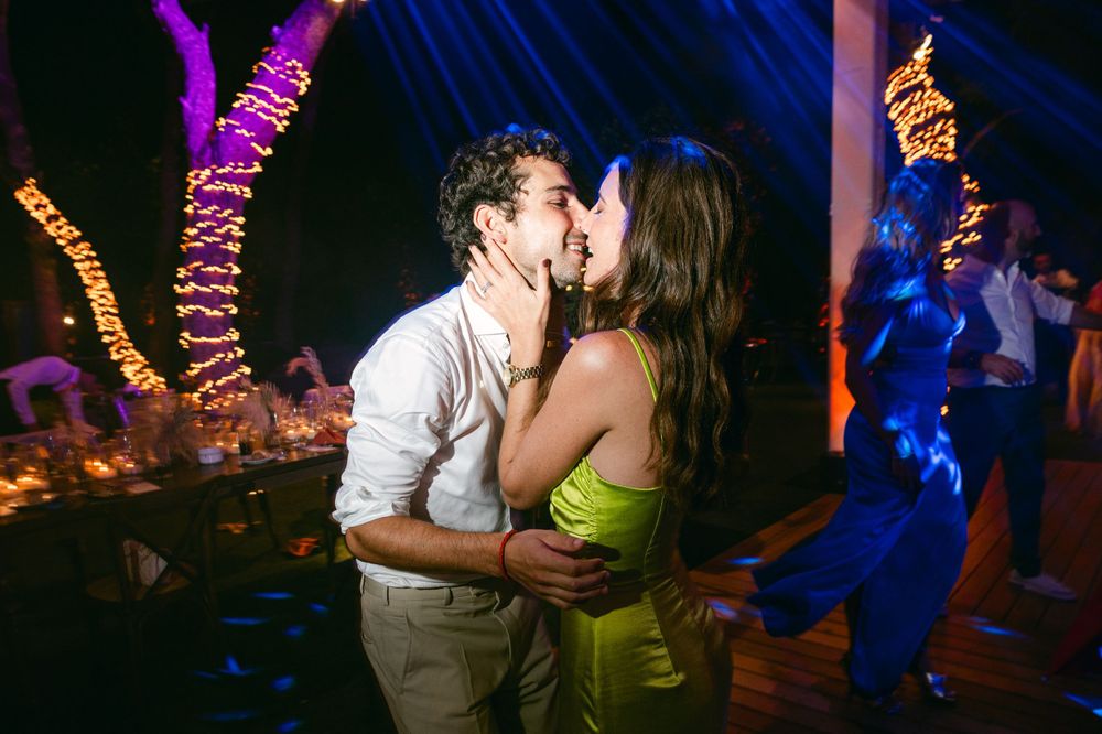 A romantic dance under colorful string lights at a nighttime celebration.