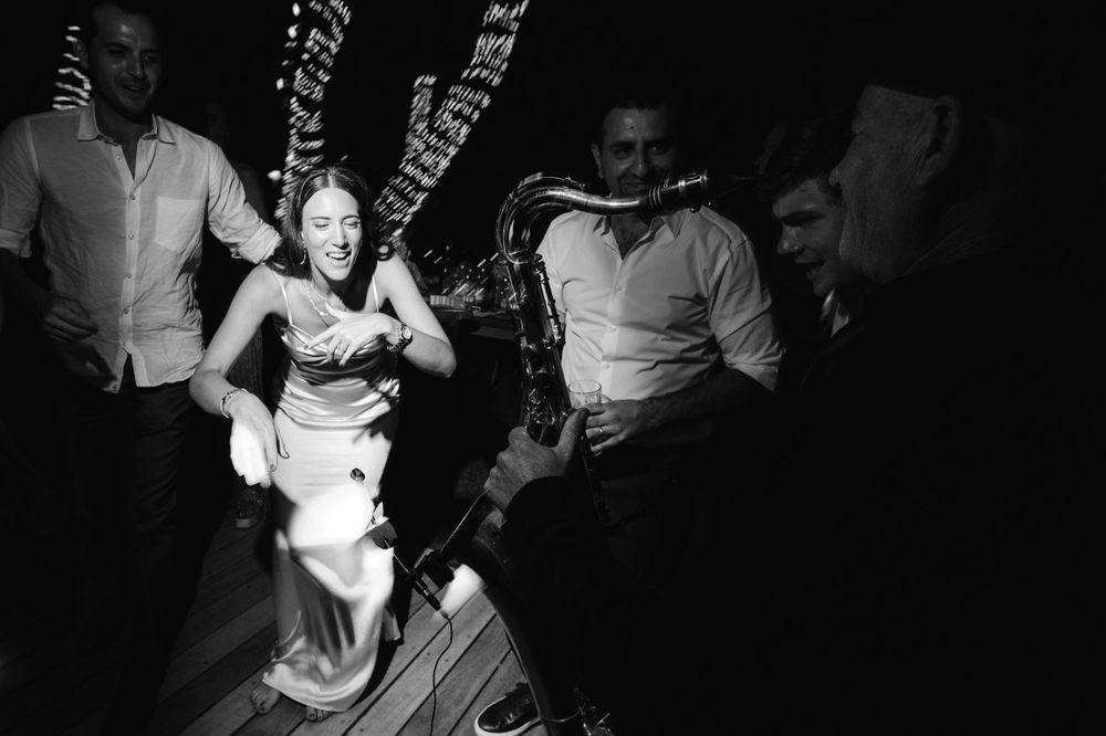 Wedding guests dancing with high energy on a wooden dance floor in black and white.