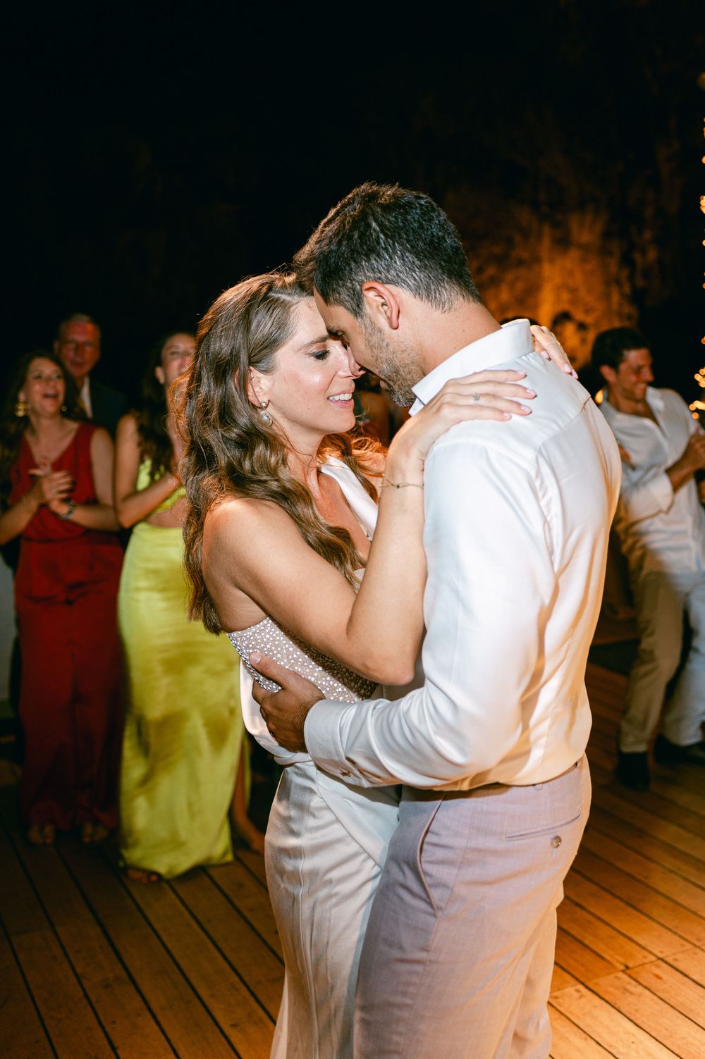 Romantic slow dance moment at an evening celebration with warm lighting.