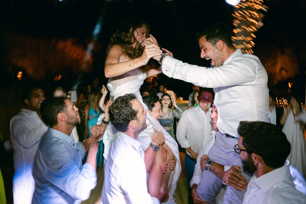 Celebration on a dance floor with guests lifting others in the air.