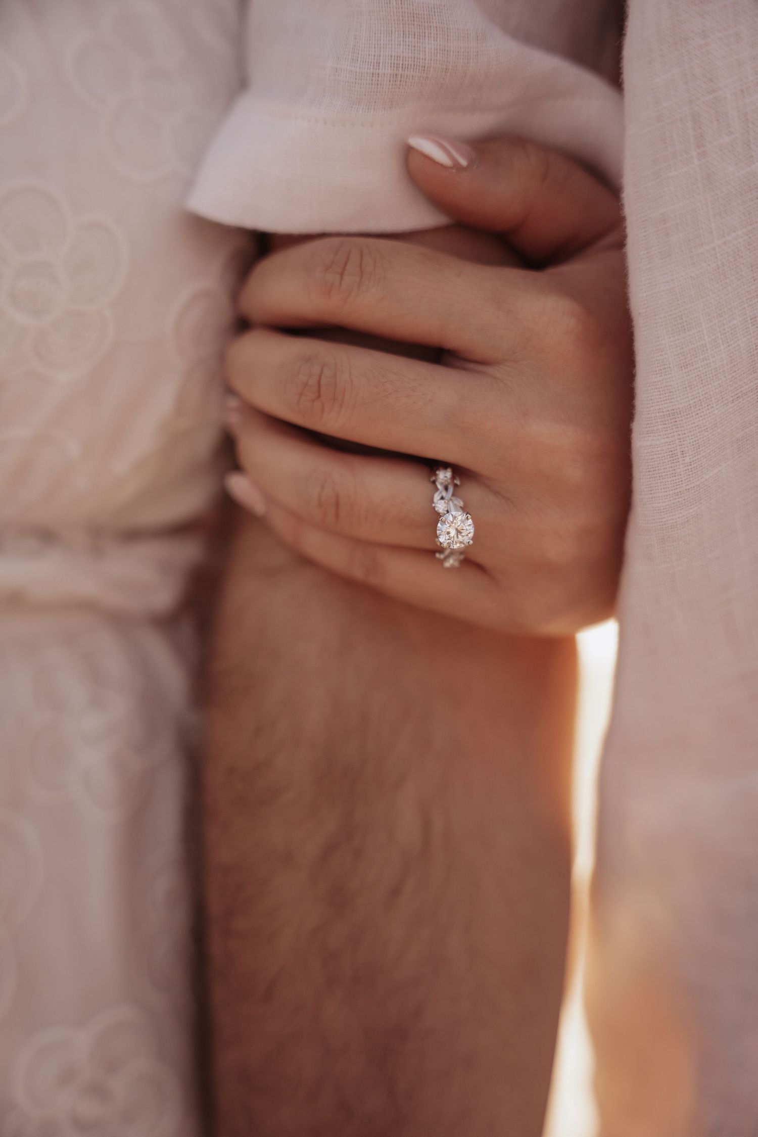 Close-up sequence of hands displaying a sparkling diamond engagement ring against a soft beige background.