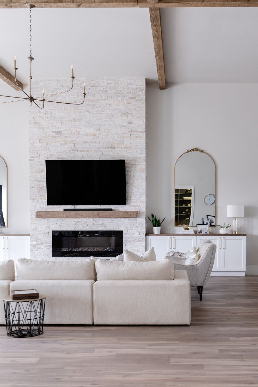 Modern living room with white brick fireplace, mounted TV, and cream-colored sectional sofa.