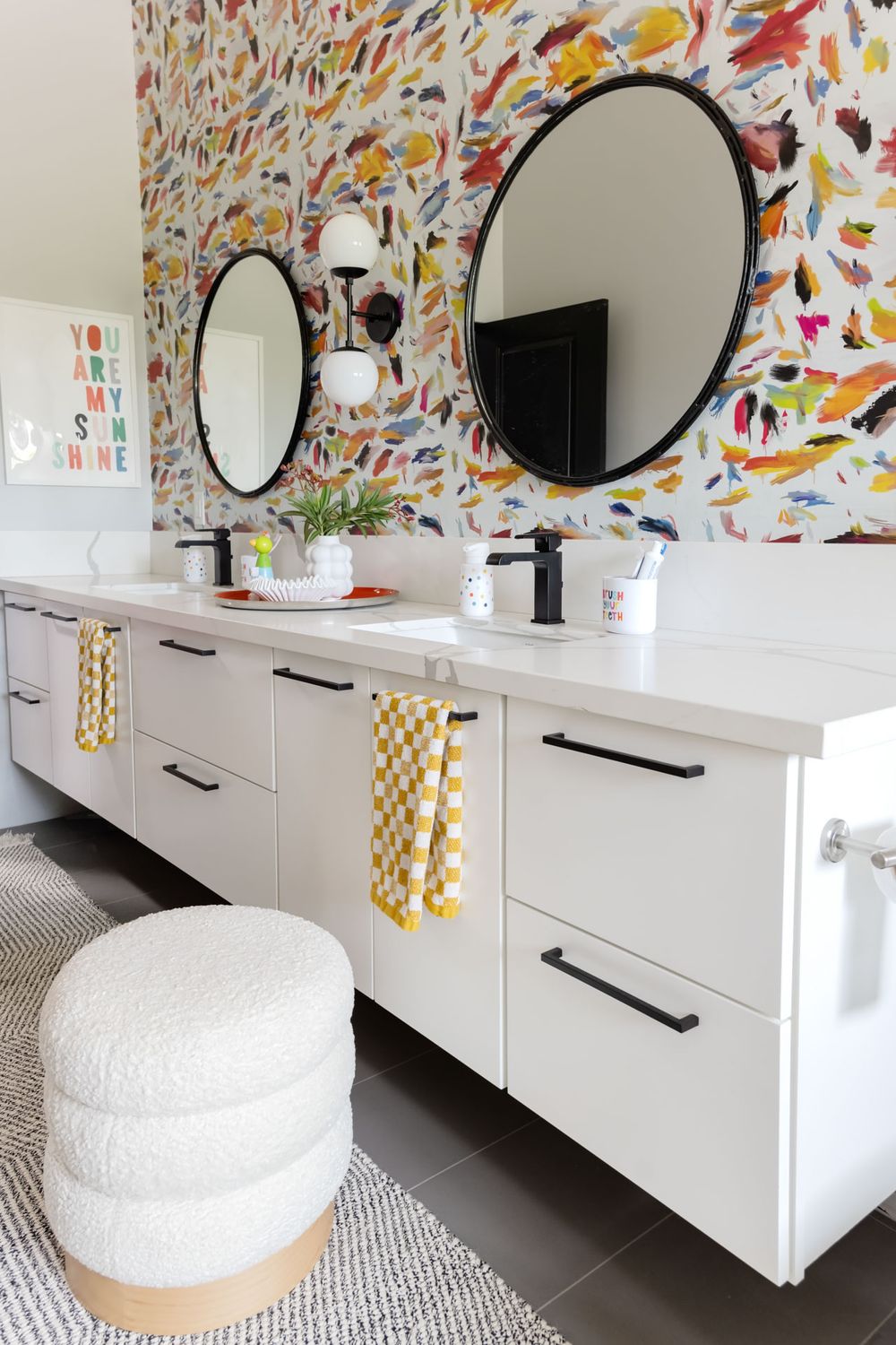 Modern bathroom vanity with round mirrors and colorful wallpaper featuring butterfly patterns.