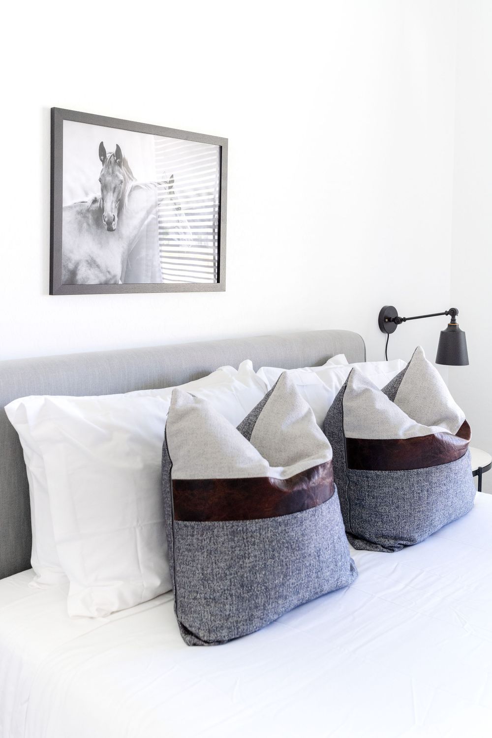 Modern bedroom with horse photograph and decorative two-toned throw pillows on bed.