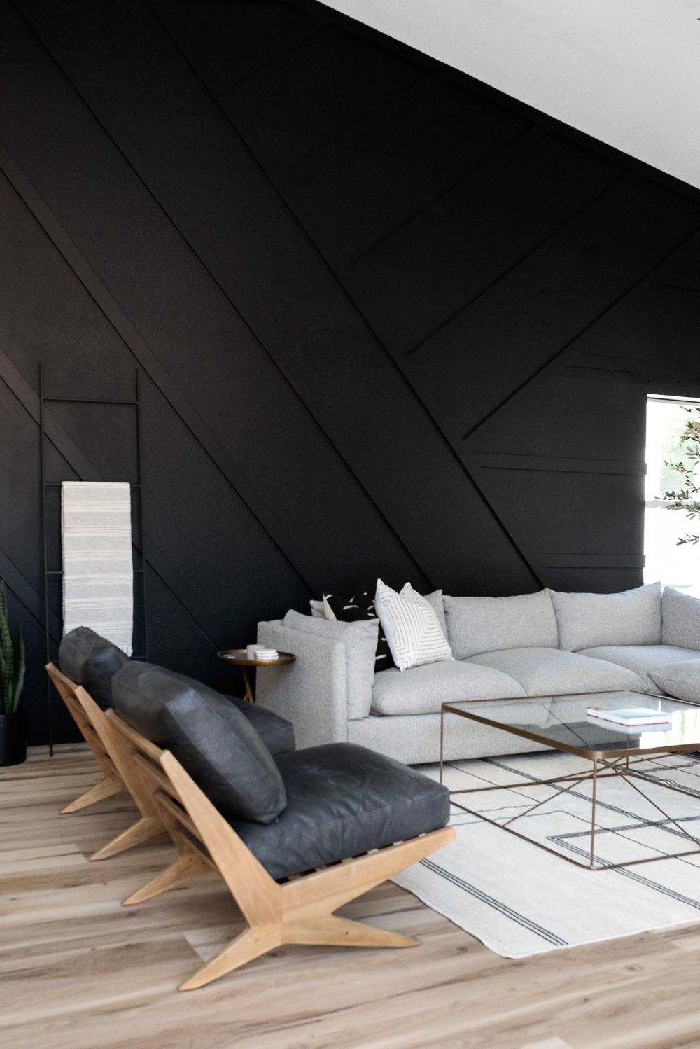 Modern living space with dramatic black geometric wall paneling and contemporary furniture.