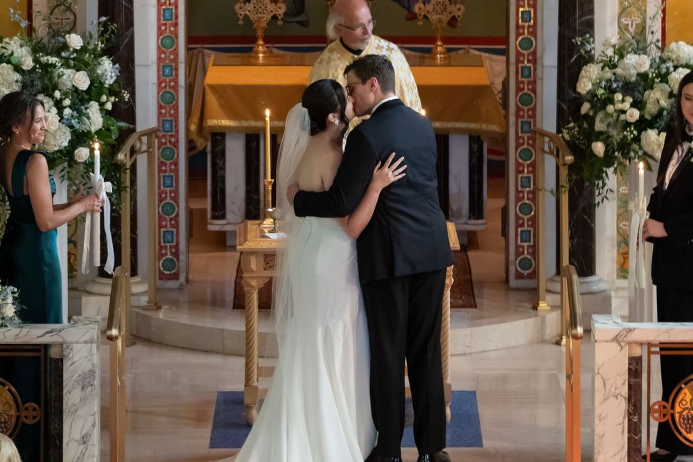 A wedding ceremony taking place in an ornate church with floral decorations.