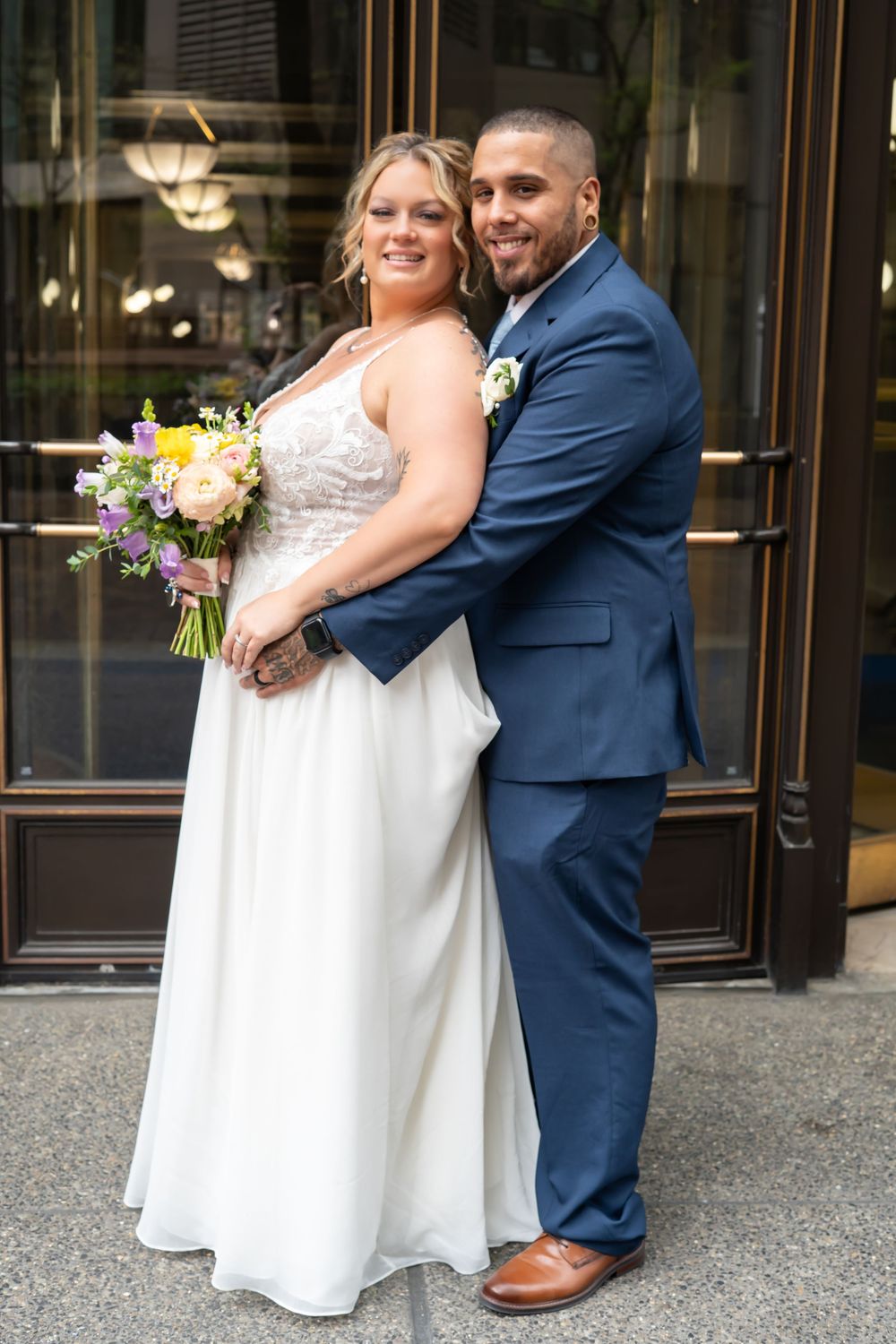 A happy wedding couple pose together outside a historic building entrance. Pittsburgh Pennsylvania