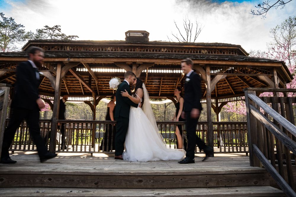 Outdoor wedding ceremony setup with wooden pavilion and natural landscaping.